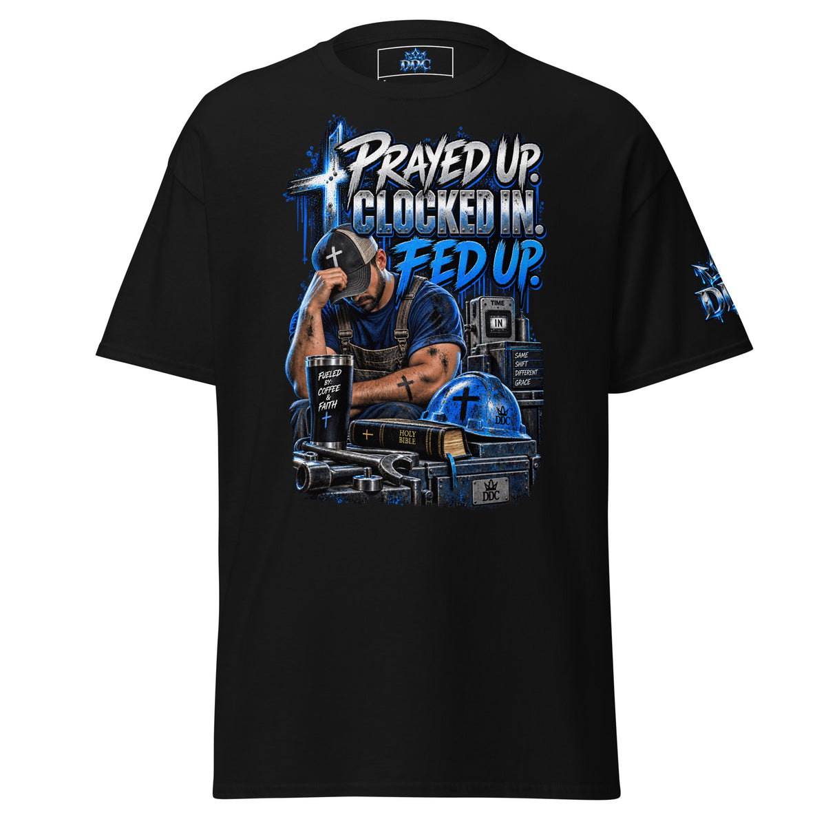 A black short-sleeve graphic t-shirt with a detailed front print featuring a man in a cap, a cross, a helmet, and the text 'PRAYED UP. CLOCKED IN.
