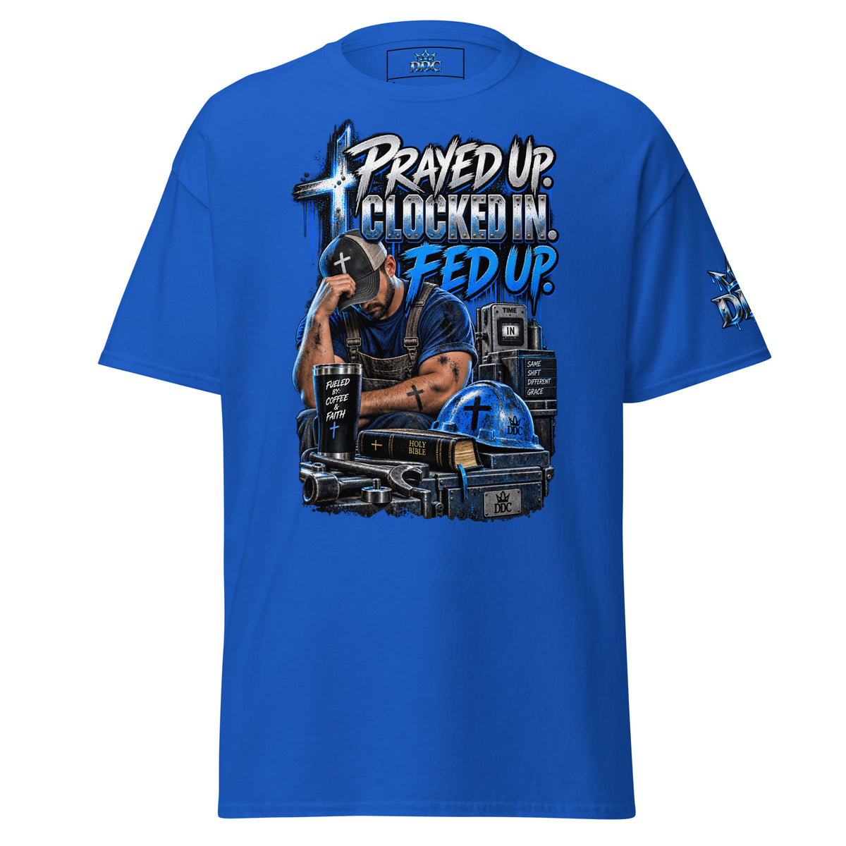 A royal blue short-sleeve t-shirt with a large graphic print on the front. The graphic features a man in a cap looking down in a distressed pose, surrounded by a tank, a cross, a Bible, and a helmet, with the text 'PRAYED UP.