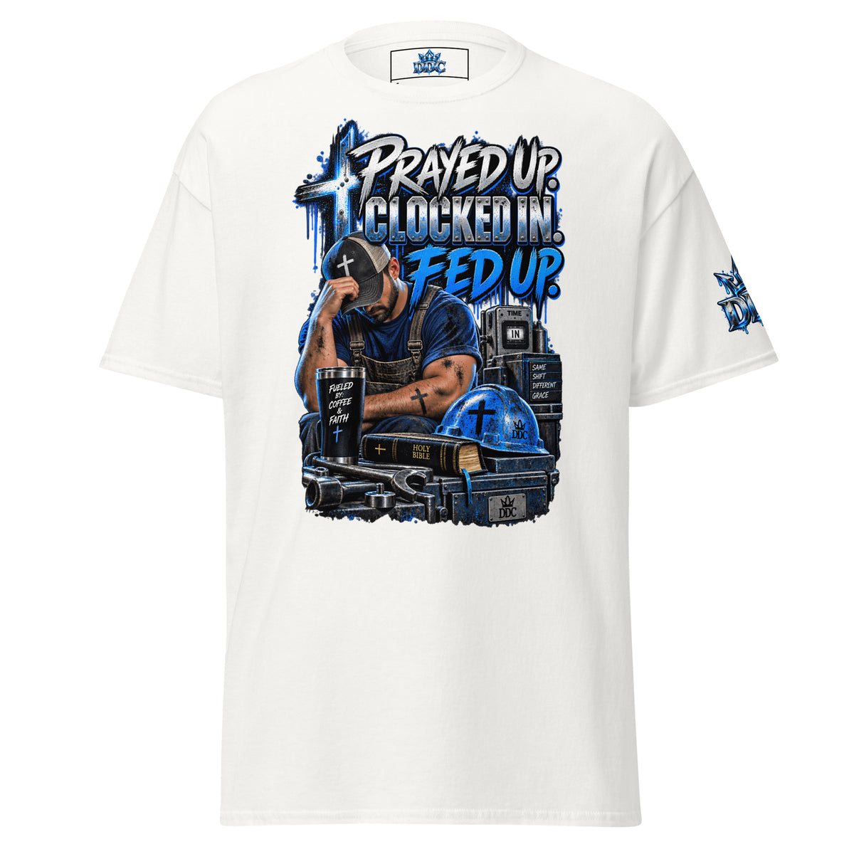 A white short-sleeve t-shirt with a large graphic print on the front. The graphic features a man in a cap looking down, surrounded by a cross, a clock, a coffee cup, and a helmet, with the text 'PRAYED UP CLOCKED IN FED UP'.