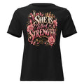 A black short-sleeve crewneck t-shirt featuring a large graphic print on the front. The graphic displays the text 'SHE IS CLOTHED IN STRENGTH' in stylized cream and pink lettering, decorated with pink roses, a gold crown, and a small cross, with 'EMMANUEL ELIZABETH' printed below.