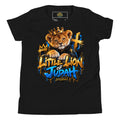 A black short-sleeve t-shirt with a colorful graphic print of a lion cub wearing a gold crown and a blue robe, with the text 'Little Lion of Judah' in a graffiti-style font. The shirt is displayed flat against a white background.