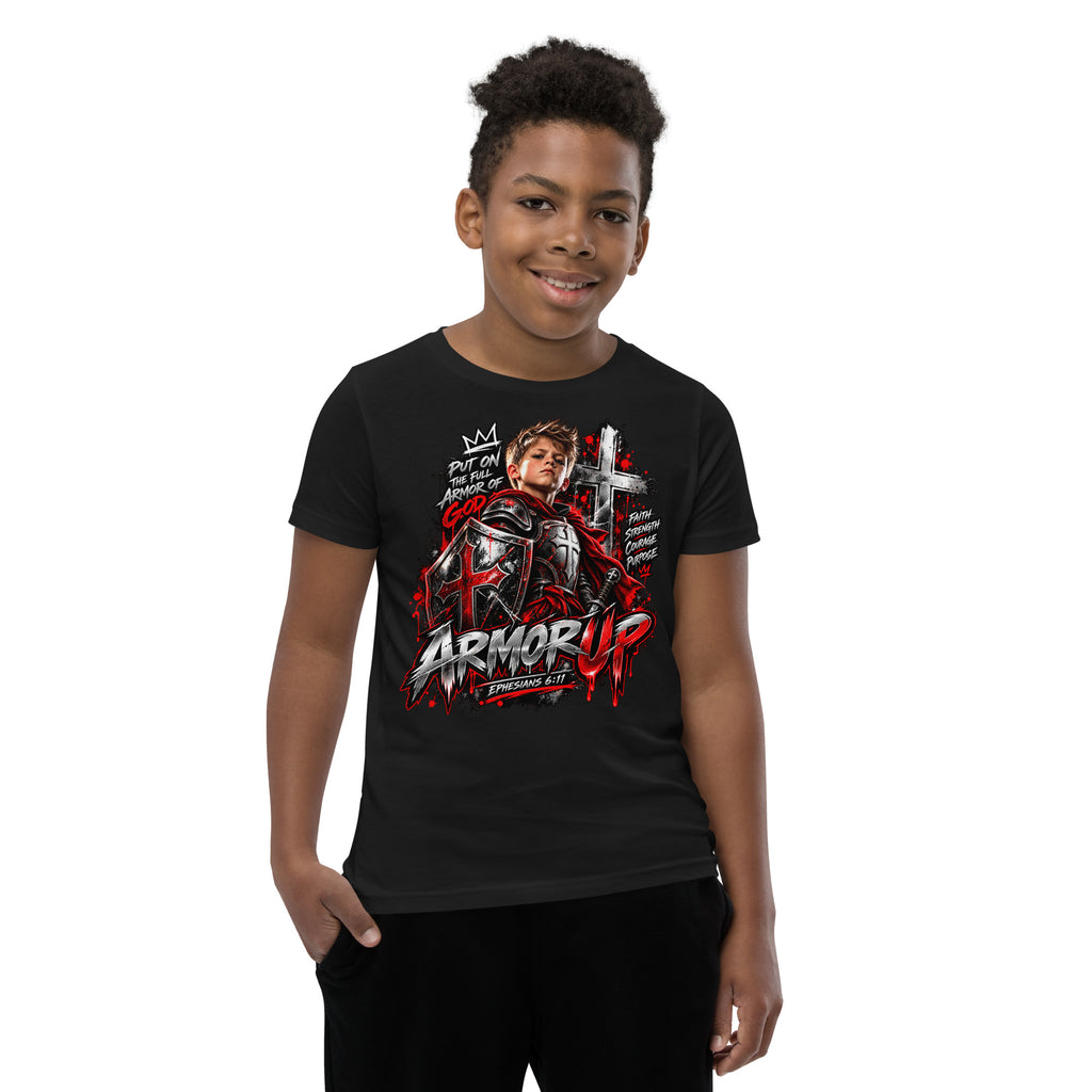 A young boy wearing a black graphic t-shirt with a red and white 'Armor Up' design, photographed against a solid white background.