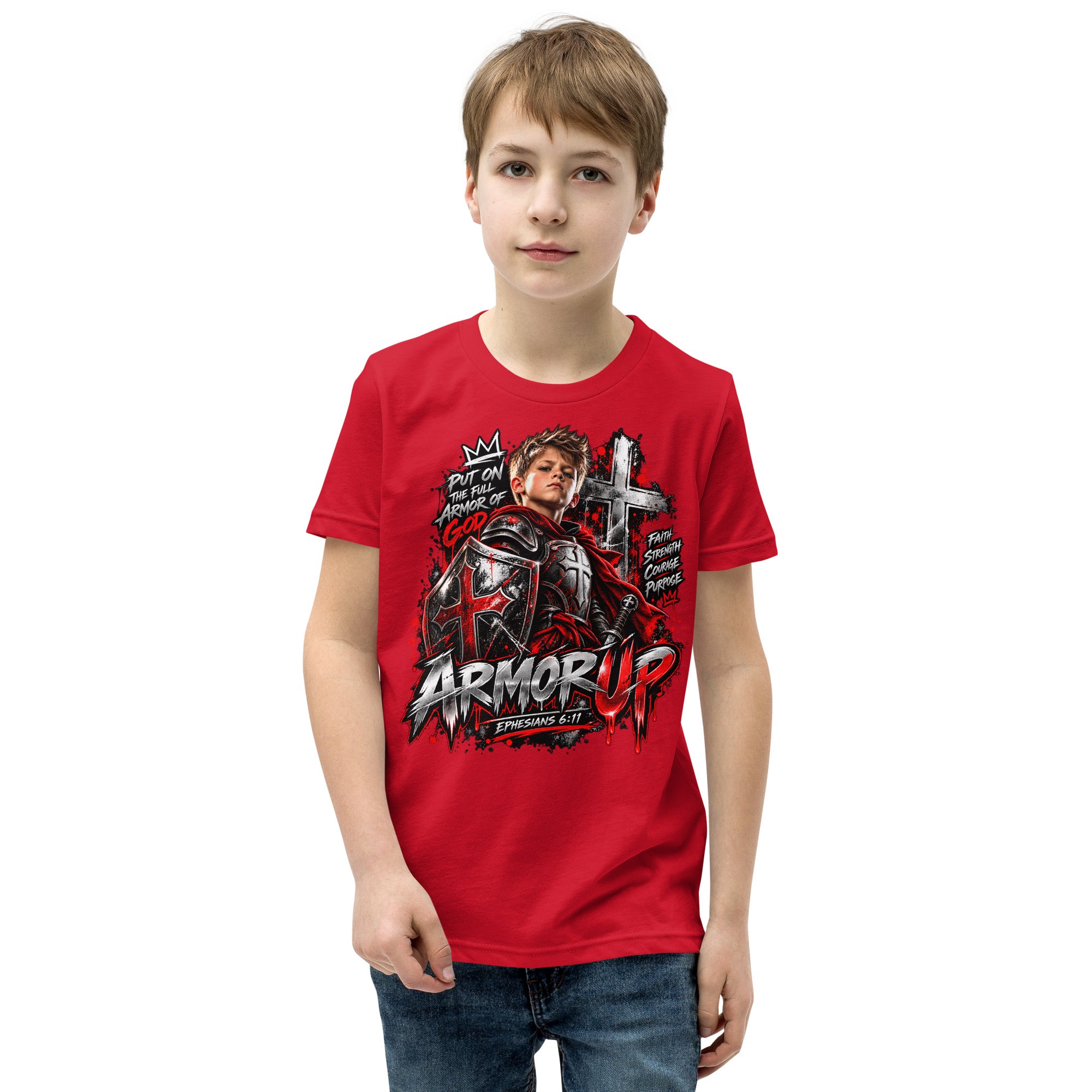 A young boy wearing a red graphic t-shirt with a 'Armor Up' design, paired with blue jeans, standing against a plain white background.